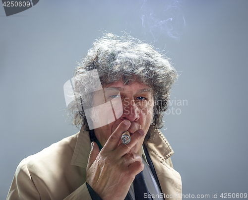 Image of The senior man with cigar as detective or boss of mafia on gray studio background