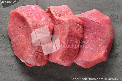 Image of three piecea of raw beef meat on shale board