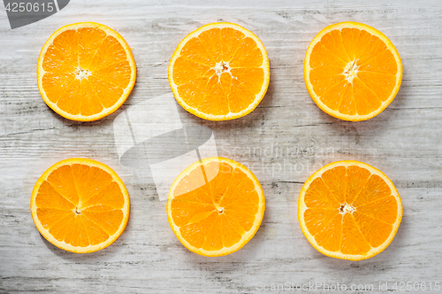 Image of Six slices of fresh oranges on white wood background
