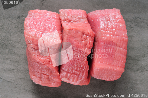 Image of three piecea of raw beef meat on shale board