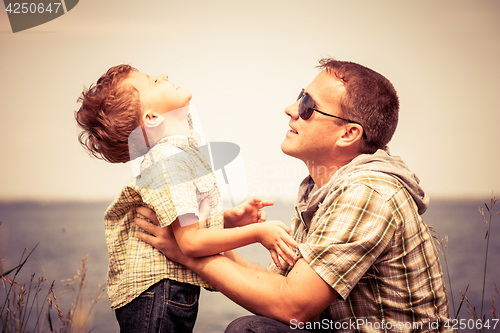 Image of Father and son playing at the park near lake at the day time.