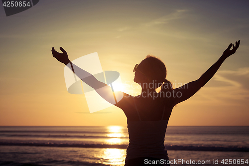 Image of woman open arms under the sunset at sea