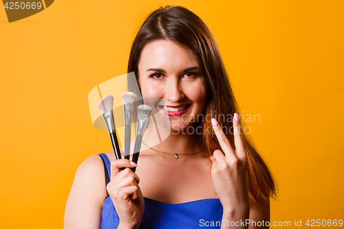 Image of Beautiful brunette with makeup brushes