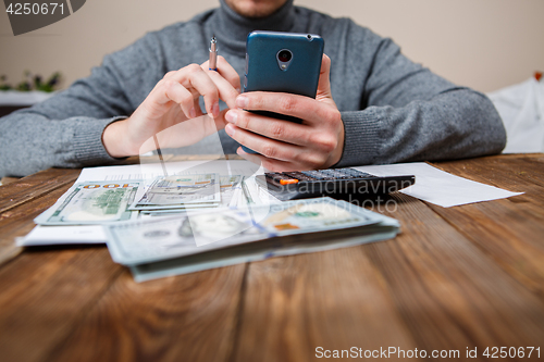 Image of savings, finances, economy and home concept - close up of hands with calculator counting money and making notes at home