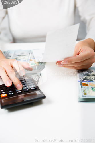 Image of savings, finances, economy and home concept - close up of hands with calculator counting money and making notes at home