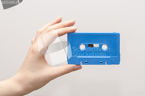 Image of hand holding blue cassette tape