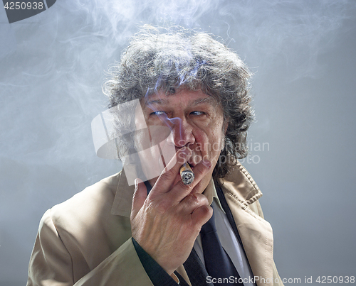 Image of The senior man with cigar as detective or boss of mafia on gray studio background