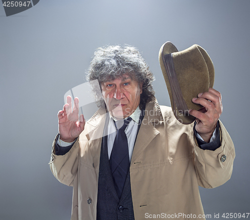 Image of The senior man as detective or boss of mafia on gray studio background