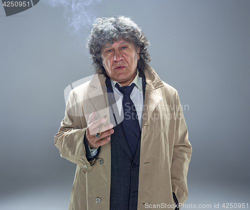 Image of The senior man with cigar as detective or boss of mafia on gray studio background