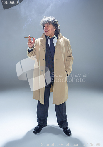 Image of The senior man with cigar as detective or boss of mafia on gray studio background