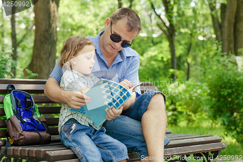 Image of Father and son playing at the park at the day time.