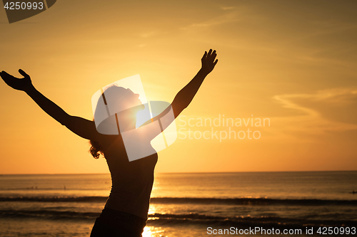 Image of woman open arms under the sunrise at sea