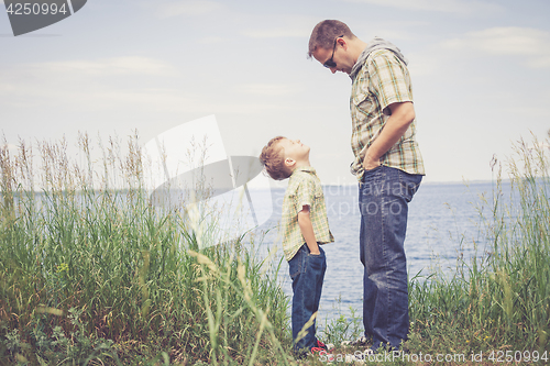 Image of Father and son playing at the park near lake at the day time.