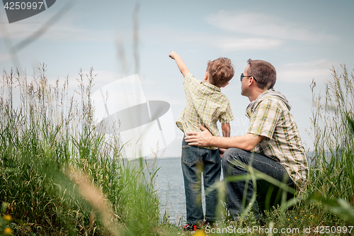 Image of Father and son playing at the park near lake at the day time.