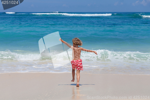 Image of Happy little boy running on the beach