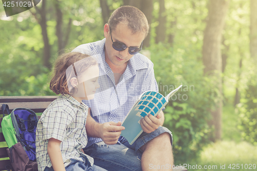 Image of Father and son playing at the park at the day time.