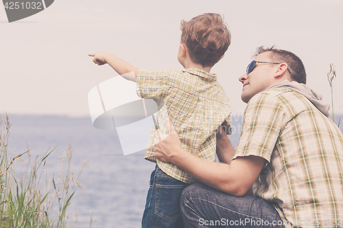 Image of Father and son playing at the park near lake at the day time.