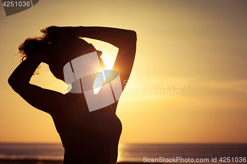 Image of woman open arms under the sunset at sea