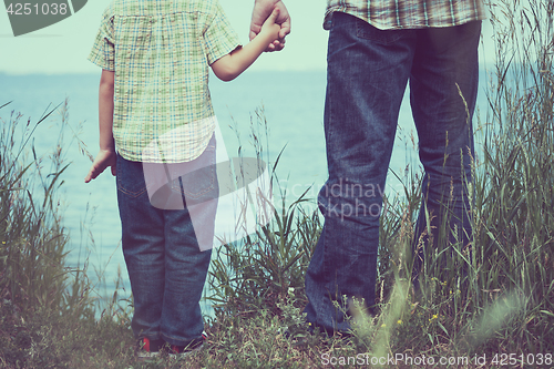 Image of Father and son playing at the park near lake at the day time.