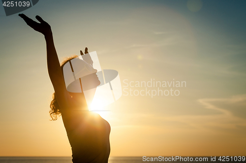 Image of woman open arms under the sunrise at sea