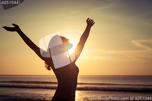 Image of woman open arms under the sunset at sea