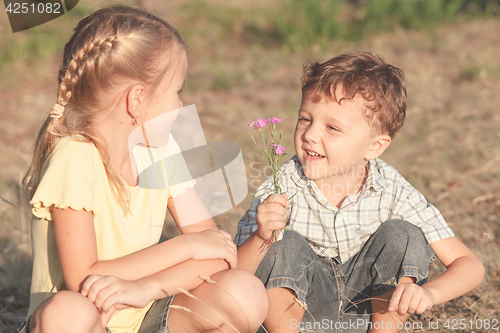 Image of Two happy children  playing near the tree