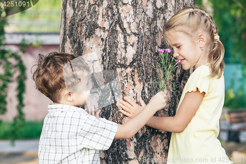 Image of Two happy children  playing near the tree 