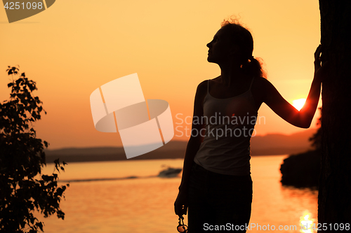 Image of Silhouette of happy woman who standing on the coast of lake