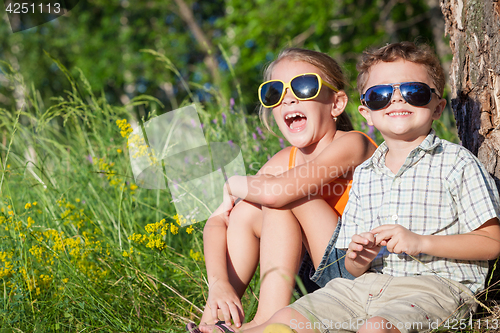 Image of Two happy children  playing near the tree at the day time.