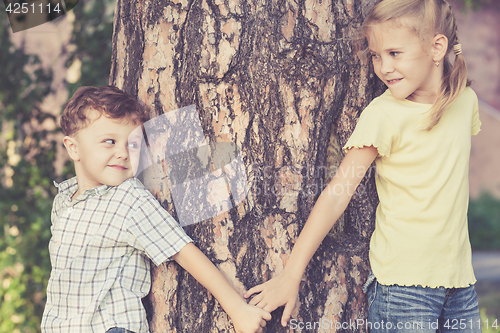 Image of Two happy children  playing near the tree