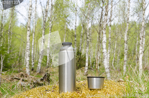 Image of Thermos with cup in a bright forest