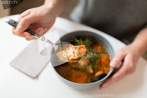 Image of woman eating seafood soup at restaurant