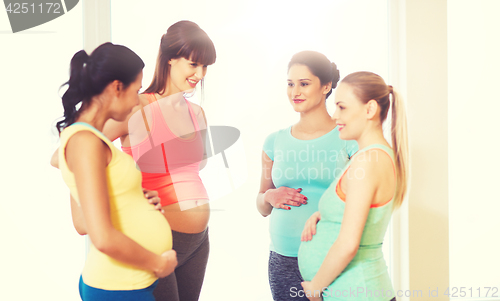 Image of group of happy pregnant women talking in gym