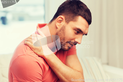 Image of unhappy man suffering from neck pain at home