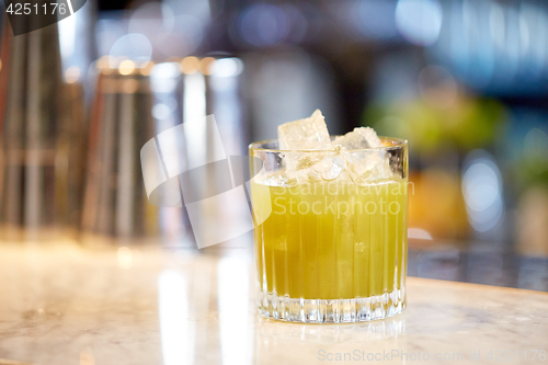 Image of glass of cocktail with ice cubes at bar