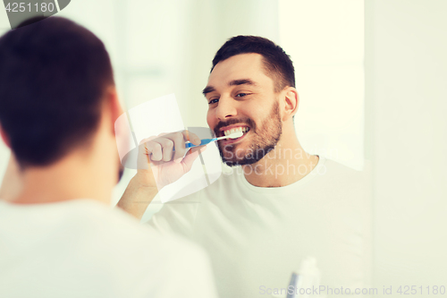 Image of man with toothbrush cleaning teeth at bathroom