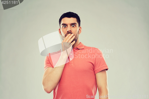 Image of scared man in polo t-shirt over gray background