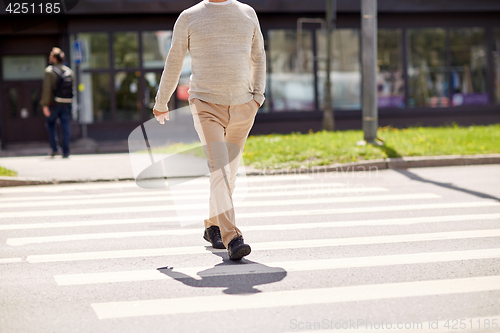 Image of senior man walking along city crosswalk