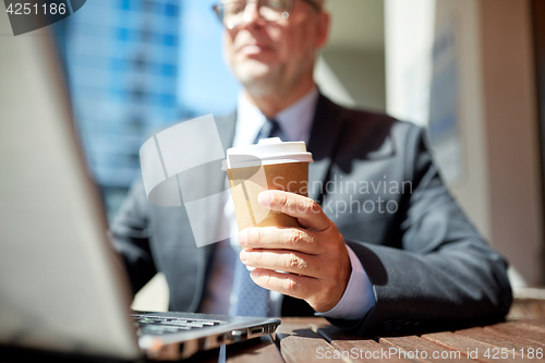 Image of senior businessman with laptop and coffee outdoors