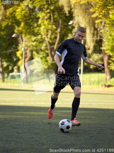 Image of soccer player playing with ball on football field