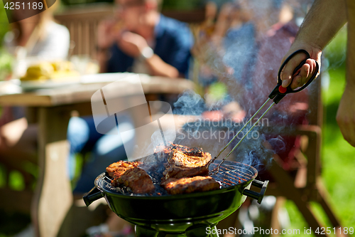 Image of man cooking meat on barbecue grill at summer party