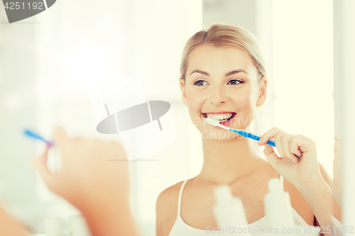 Image of woman with toothbrush cleaning teeth at bathroom