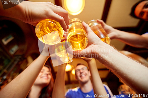 Image of football fans clinking beer glasses at sport bar