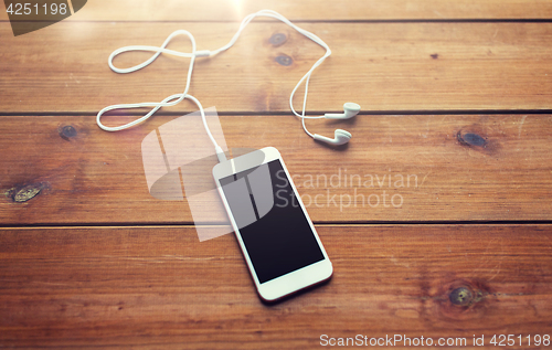 Image of close up of blank smartphone and earphones on wood