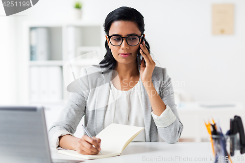 Image of businesswoman calling on smartphone at office