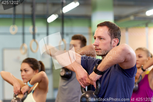 Image of group of people with kettlebells exercising in gym