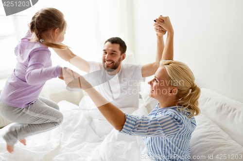 Image of happy family having fun in bed at home