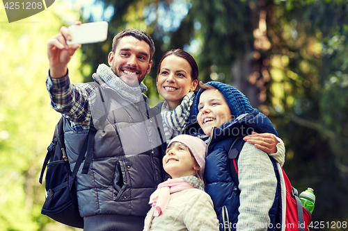 Image of family taking selfie with smartphone in woods