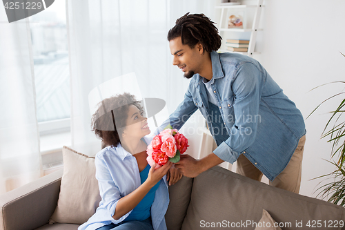 Image of happy couple with bunch of flowers at home