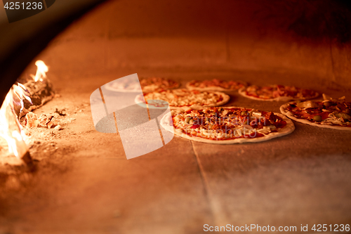 Image of pizza baking in oven at pizzeria